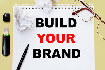 points , flash drive, notepad and paper on the table. Business concept. Text BUILD YOUR BRAND.