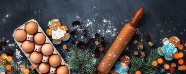 Christmas gingerbread on dark background with spruce branches top view. Holiday celebration and cooking concept