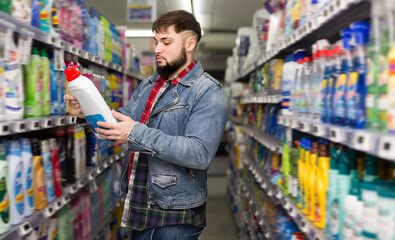 Interested young man making purchases in household chemistry store