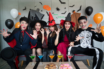 Young Asian people, a group of five people, in scary costumes. Group of friends wearing Halloween clothes preparing to join a party.