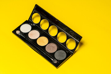 Obraz na płótnie Canvas Close-up of eyeshadow palettes with brushes isolated on yellow background. Beauty industry and make-up products.