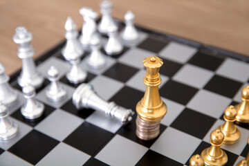 The silver queen pawn on the chess board kneels to the golden queen pawn standing on the coin