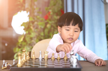 Cute Chinese little girl learning to play chess