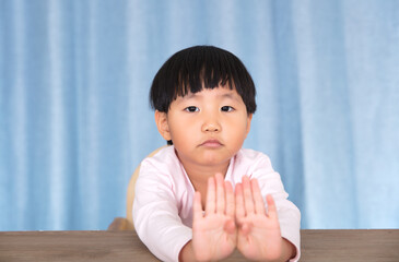 Cute little Chinese girl looking at the camera with both hands making rejection gesture