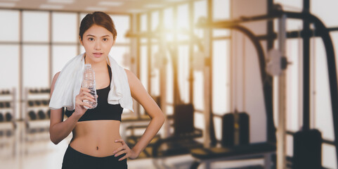 Fototapeta na wymiar Portrait of asian young beautiful drinking water during traning in the gym background.