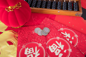 Red envelopes and traditional abacus and red lanterns and coins on red spring couplets background. The Chinese character on the red envelopes and spring couplets mean "happiness"