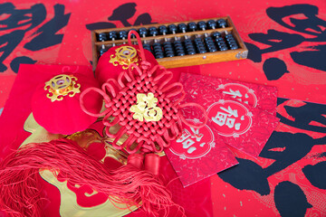 Looking down on Chinese knots and red envelopes, abacus and small lanterns on the table.The Chinese character on the Chinese knot means "happiness"