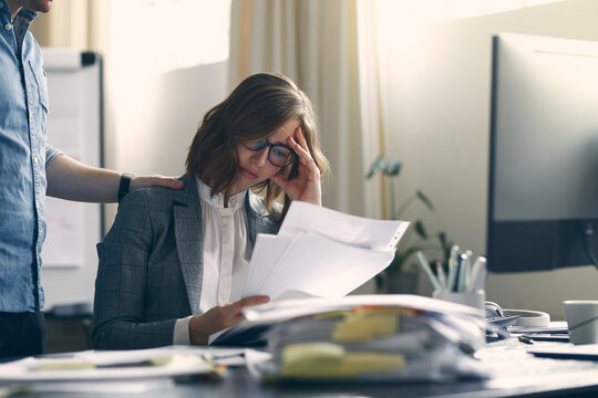 Male Colleague Trying To Comfort Businesswoman And Employee Who Is Depressed, Stressed And Sad About All Her Work. Concept: Too Much Work - Cannot Do It. 