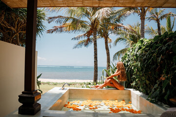 Young woman enjoying in outdoor luxury spa. Beautiful luxury stone bath tub with tropical  sea view