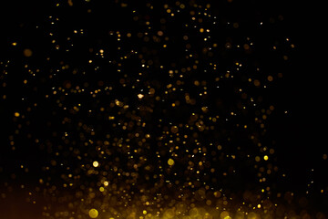 Naklejka na ściany i meble Sparkling golden glittering effect isolated on black background.