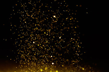 Naklejka na ściany i meble Sparkling golden glittering effect isolated on black background.