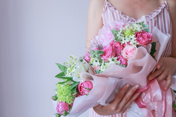 Girl in a pink sundress holds a pink green bouquet in her hands