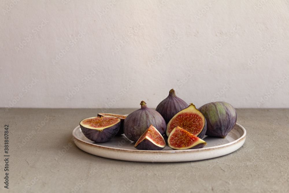 Wall mural Fresh figs on a plate on a light concrete background