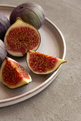 Fresh figs on a plate on a light concrete background