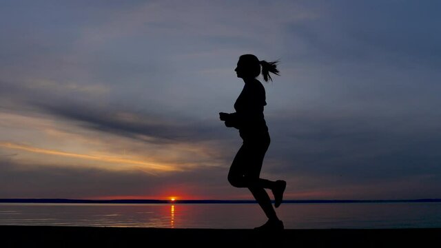 Woman Running Alone at Beautiful Sunset in the Beach. Silhouette of Athlete Training on Dusk