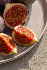 Fresh figs on a plate on a light concrete background