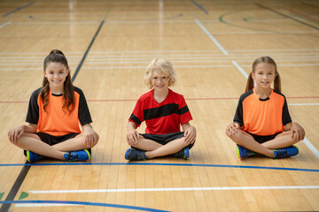 Kids in bright sportswear sitting in lotus pose