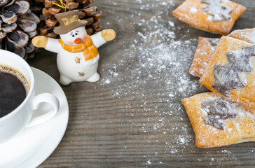 Christmas breakfast with coffee and pastries. White toy snowman and pine cones on a wooden table create a festive atmosphere