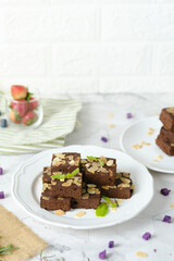 Squares Chocolate brownie with almond sliced set on white cafe table.