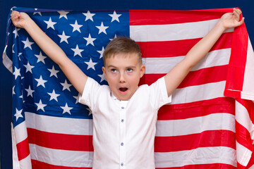Boy 9s holding big American flag, on blue and boy shouts