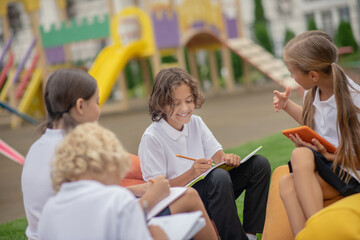 Group of pupils sitting outside and preparing homework