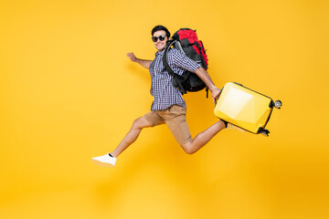 Young excited Caucasian male tourist with baggage jumping in mid-air isolated on colorful studio...