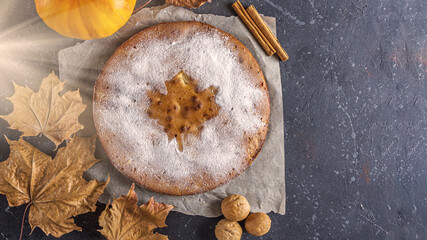American homemade pumpkin or apple pie with walnut and autumn dry leaves on rustic table. Thanksgiving dish. Autumn harvest festival. Copy space for text