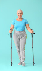 Mature woman with walking poles on color background