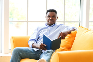 African-American man reading book at home