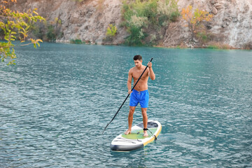 Young man using paddle board for sup surfing in river