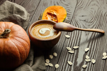 Pumpkin soup in wooden bowl and fresh pumpkins