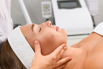 Fototapeta na wymiar Beautician hands massage client face and chin