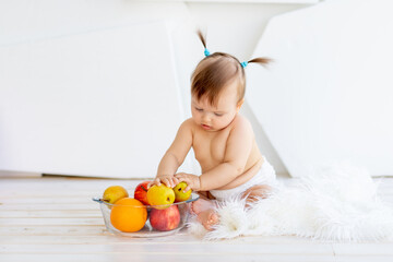a little girl in a bright room sitting with a plate of fruit