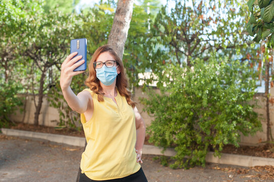 Mujer tomándose un selfie con mascarilla en exteriores