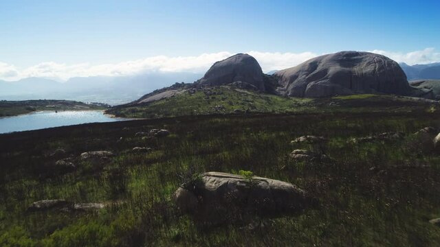 Aerial - Flying low over burnt fynbos, dam and granite monolith of Paarl Mountain in background