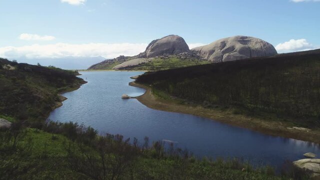 Aerial - Flying towards beautiful dam on Paarl Mountain, with imposing granite monolith in background, burnt fynbos vegetation visible
