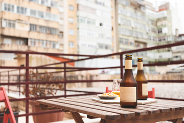 Home made preparation of an aperitif outside the balcony. Two beers on a wooden table for business people after work. Some peanuts in the bowl. Lisbon, Portugal