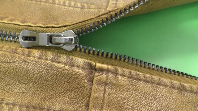 The zipper opens on the brown leather jacket. Green background. Chromakey.