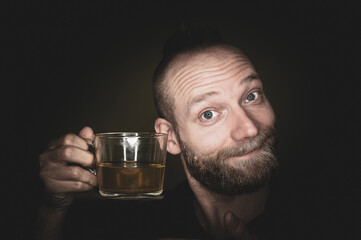 A friendly guy smiles at the camera and offers tea.