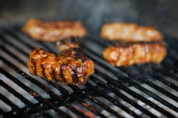 Shallow depth of field (selective focus) image with Romanian traditional mici (mititei), grilled ground meat rolls in cylindrical shape on the barbecue grill.