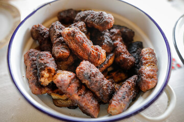 Shallow depth of field (selective focus) image with Romanian traditional mici (mititei), grilled ground meat rolls in cylindrical shape on the barbecue grill.