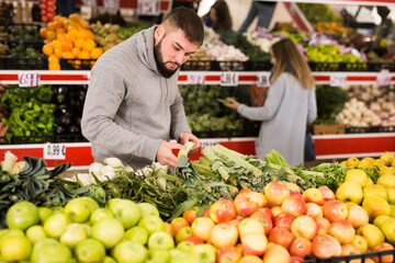 Fototapeta na wymiar Adult man is choosing leek and celery in the grocery store. High quality photo