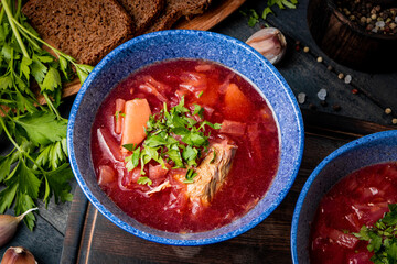  Borscht with sour cream on a black wooden table close-up - a dish of traditional Russian and Ukrainian cuisine. Red soup.