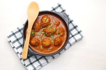 Indian cuisine - Kashmiri Dum Aloo or Potatoes in red gravy over white background. Garnished with coriander. Serve hot with rice or Naan/roti. Copy space. Panjabi Dam alu curry.
