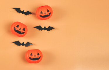 flat lay of Halloween pumpkins , black paper bats, on orange background with copy space.. Halloween concept.