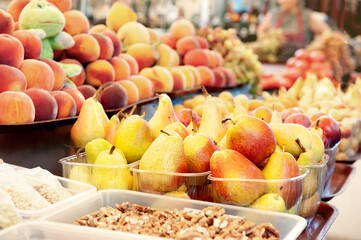 Ripe yellow pears and peaches lie on the market counter with other fruits. Farmer's harvest at the...