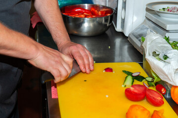 chef is cutting vegetables on a plastic yellow cutting Board