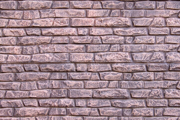 A modern stone fence in the form of an aged stone fence painted with light pink paint.