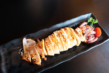 grilled squid with teriyaki sauce on black plate . Japanese seafood . - 381830037