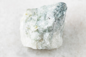 closeup of sample of natural mineral from geological collection - rough Carbonatite rock on white marble background